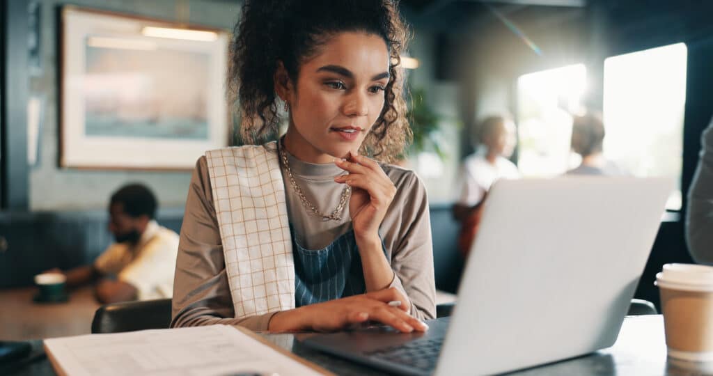 A woman looking at her laptop researching restaurant financing options for expanding dining businesses.